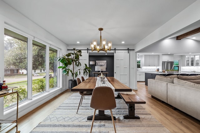 dining room with recessed lighting, a chandelier, a barn door, and light wood-style flooring