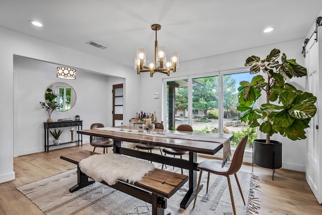 dining room with visible vents, light wood-type flooring, a barn door, a notable chandelier, and recessed lighting