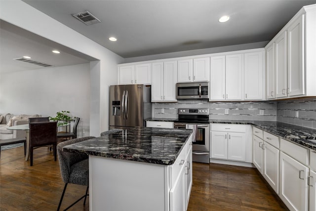 kitchen featuring backsplash, white cabinets, appliances with stainless steel finishes, and visible vents