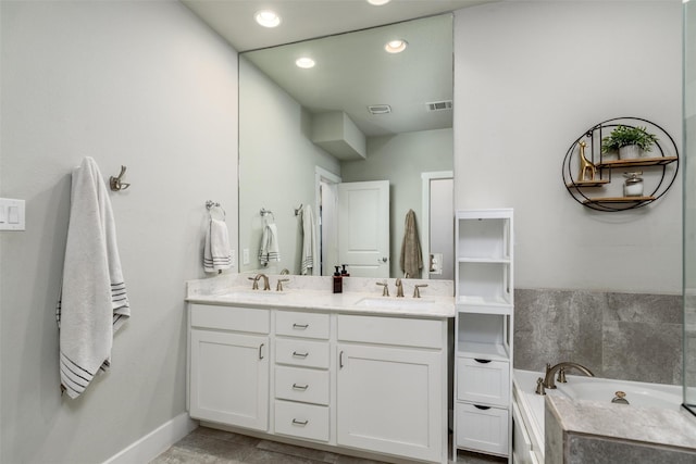 bathroom with visible vents, double vanity, a sink, and baseboards