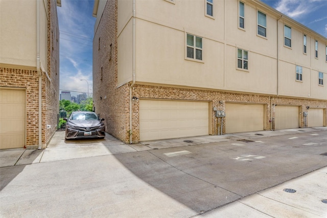 view of side of property featuring a garage, driveway, and brick siding