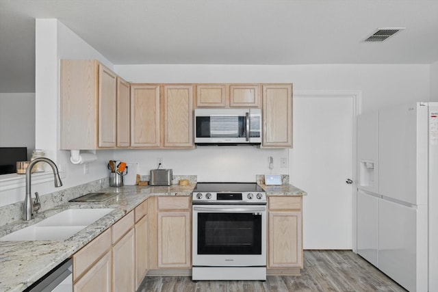 712 Riverflat Dr, Fort Worth, TX 76179 - kitchen with light brown cabinetry, a sink, light wood finished floors, stainless steel appliances, and visible vents