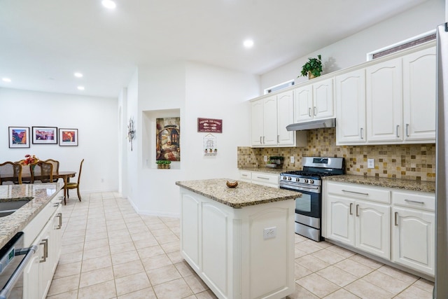 5624 Big River Dr, The Colony, TX 75056 - kitchen with under cabinet range hood, gas stove, light tile patterned flooring, a kitchen island, and backsplash