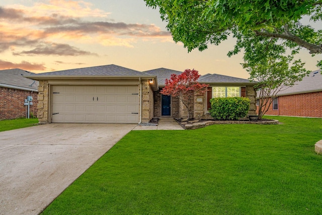 view of front of home with an attached garage, a yard, driveway, and brick siding