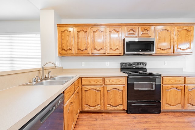 kitchen featuring a sink, light wood finished floors, appliances with stainless steel finishes, and light countertops