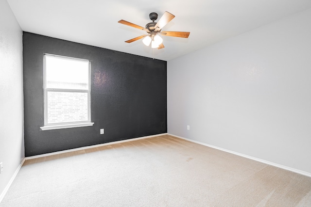 carpeted spare room featuring a ceiling fan and baseboards
