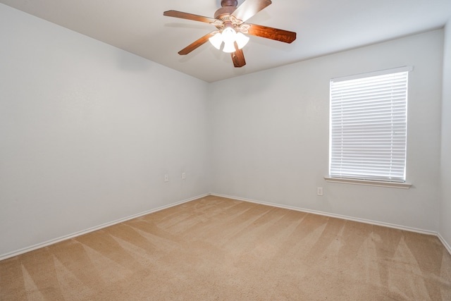 unfurnished room featuring a healthy amount of sunlight, baseboards, a ceiling fan, and light colored carpet