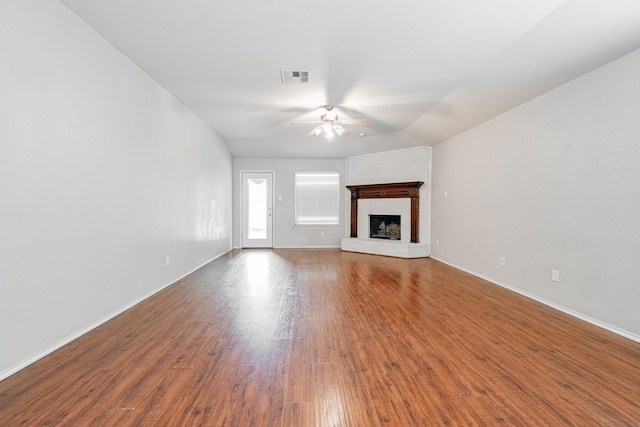 unfurnished living room featuring visible vents, a fireplace, baseboards, dark wood-type flooring, and a ceiling fan