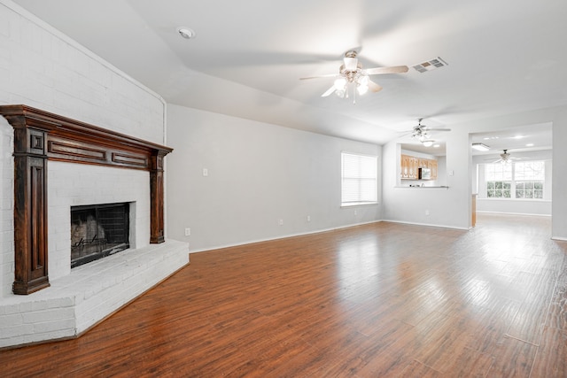 unfurnished living room featuring a wealth of natural light, ceiling fan, a fireplace, and visible vents