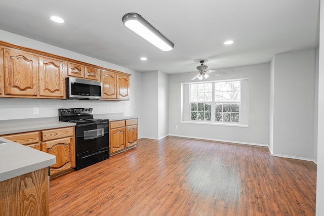 kitchen featuring ceiling fan, electric range, light countertops, stainless steel microwave, and light wood-style flooring