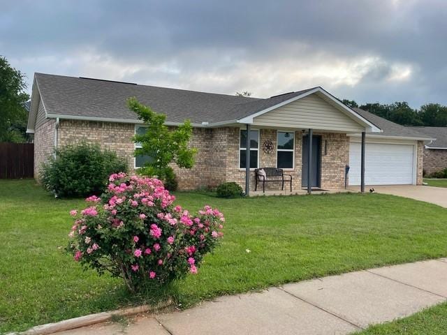 ranch-style home featuring brick siding, an attached garage, driveway, and a front lawn