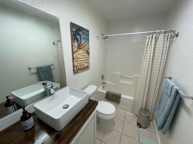 bathroom with a textured wall, vanity, toilet, tile patterned floors, and shower / bath combo with shower curtain