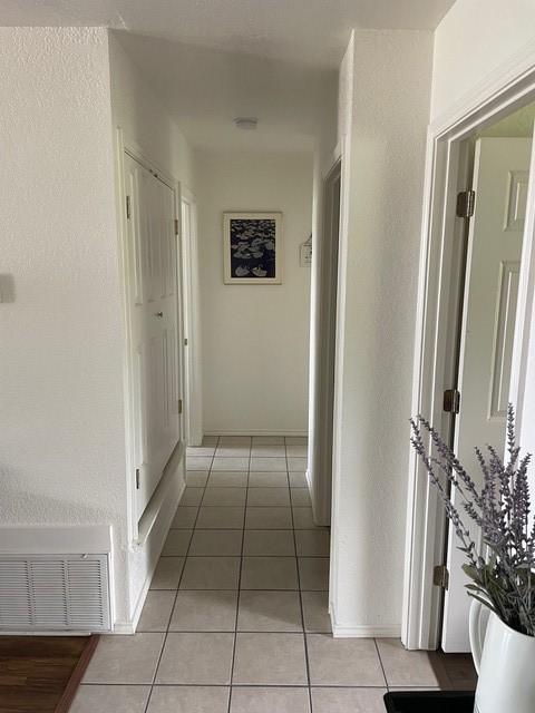 corridor featuring visible vents and light tile patterned floors