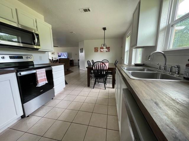 kitchen with visible vents, appliances with stainless steel finishes, hanging light fixtures, a sink, and light tile patterned flooring