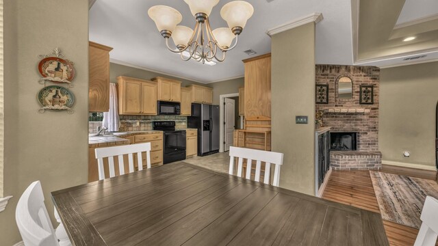 1821 Sandpiper Dr, Weatherford, TX 76088 - dining room featuring a chandelier, crown molding, a brick fireplace, light wood finished floors, and baseboards