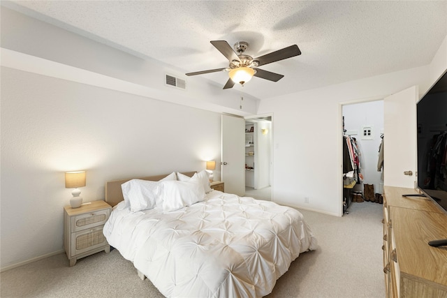 bedroom featuring visible vents, a closet, ceiling fan, light colored carpet, and a spacious closet