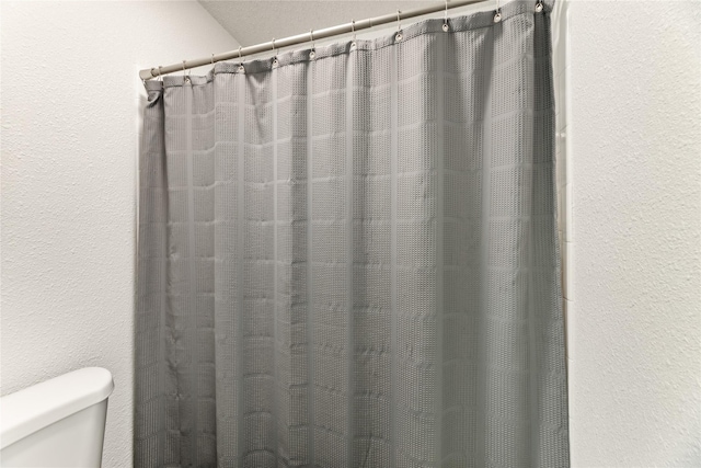 full bath with a shower with shower curtain and toilet