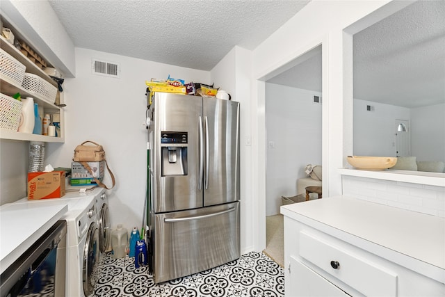 kitchen with washing machine and clothes dryer, stainless steel refrigerator with ice dispenser, a textured ceiling, and visible vents