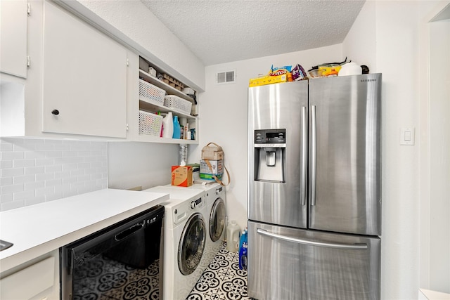 clothes washing area with washing machine and clothes dryer, a textured ceiling, visible vents, and laundry area