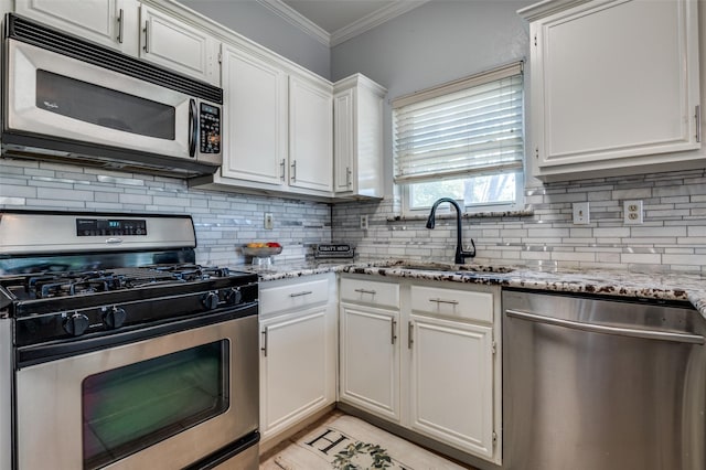 1521 Merritt Dr, Flower Mound, TX 75028 - kitchen featuring appliances with stainless steel finishes, crown molding, a sink, decorative backsplash, and white cabinets