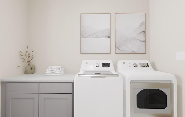 laundry area with independent washer and dryer and cabinet space