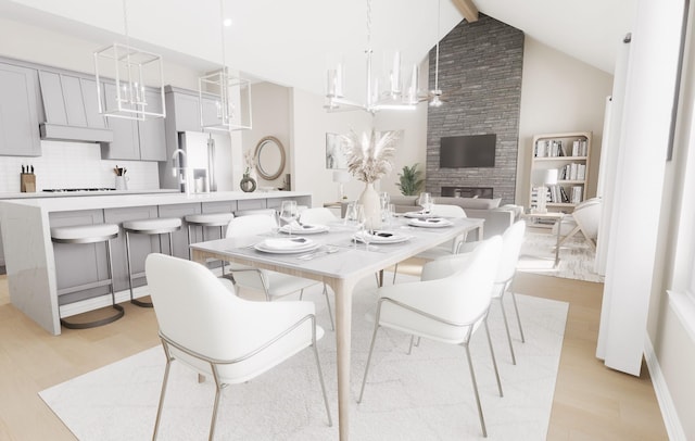 dining space featuring an inviting chandelier, a large fireplace, and light wood-style floors