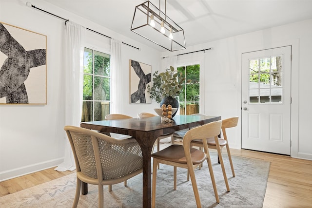 dining space with baseboards, plenty of natural light, and light wood-style floors