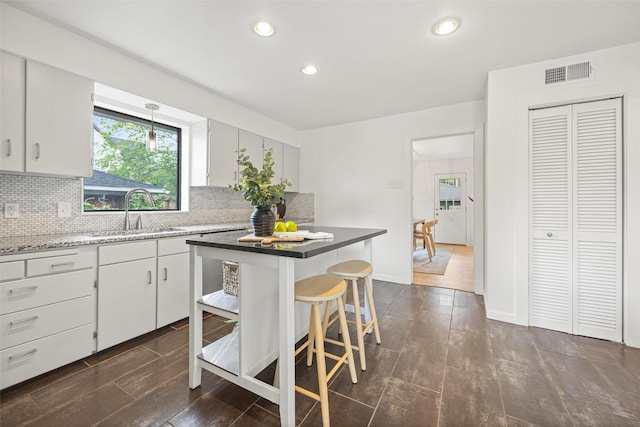 kitchen with visible vents, decorative backsplash, a breakfast bar area, recessed lighting, and a sink