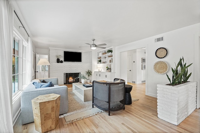 living room with visible vents, a fireplace, baseboards, ceiling fan, and light wood-type flooring