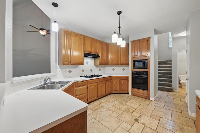 kitchen with a sink, light countertops, under cabinet range hood, black appliances, and stone tile flooring