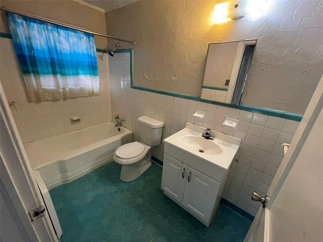 full bath with a textured wall, vanity, toilet, shower / bath combination, and tile walls