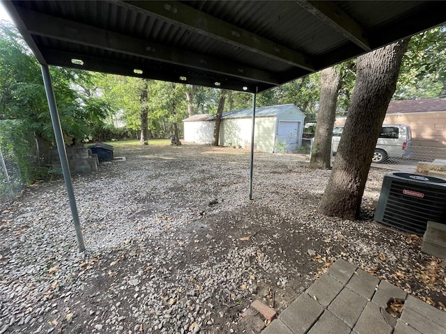 view of yard with central air condition unit, a carport, and an outbuilding