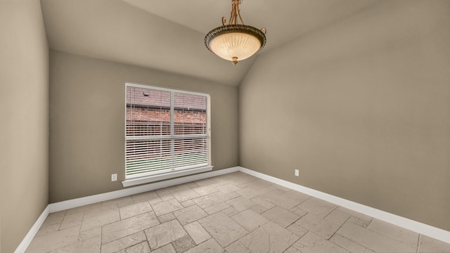 empty room with baseboards, vaulted ceiling, and stone tile floors