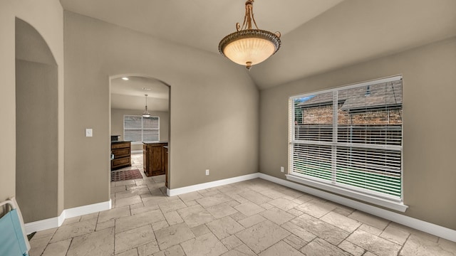 unfurnished room with baseboards, arched walkways, and stone tile flooring