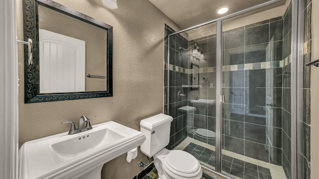 full bathroom featuring a sink, a textured wall, a stall shower, and toilet