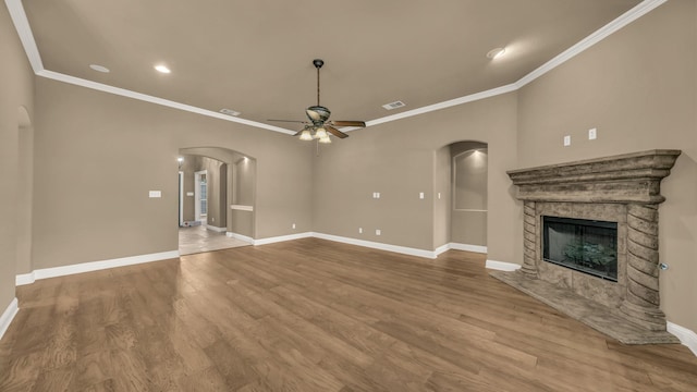 unfurnished living room with baseboards, arched walkways, and a ceiling fan