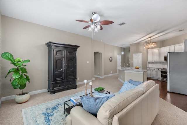 living room featuring arched walkways, baseboards, a ceiling fan, and visible vents