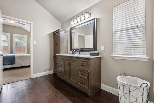 bathroom with ceiling fan, vaulted ceiling, wood finished floors, baseboards, and ensuite bath