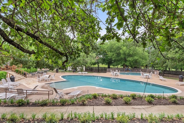 community pool with a patio and fence