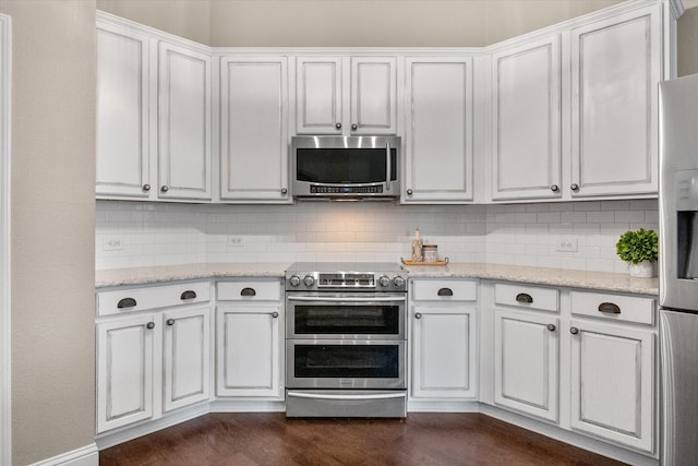kitchen with backsplash, white cabinets, appliances with stainless steel finishes, and light stone countertops