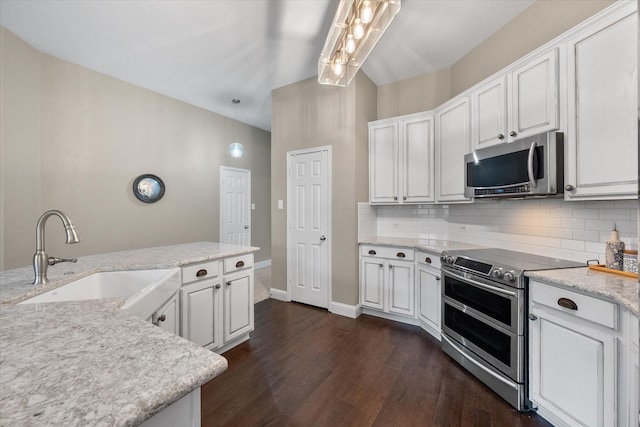 kitchen featuring appliances with stainless steel finishes, a sink, dark wood finished floors, white cabinetry, and decorative backsplash