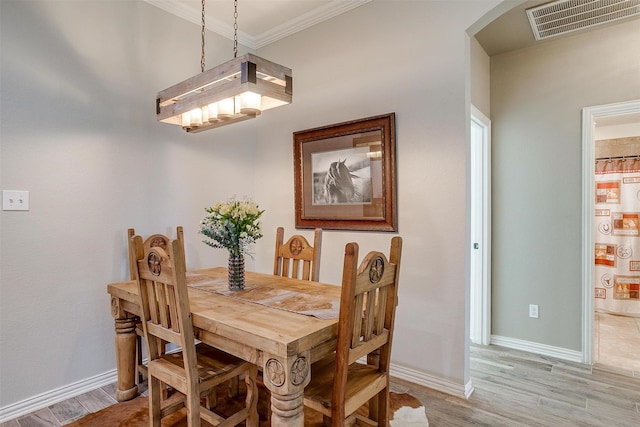 dining space featuring visible vents, arched walkways, light wood-type flooring, water heater, and ornamental molding