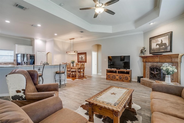 living room featuring crown molding, arched walkways, a ceiling fan, and visible vents