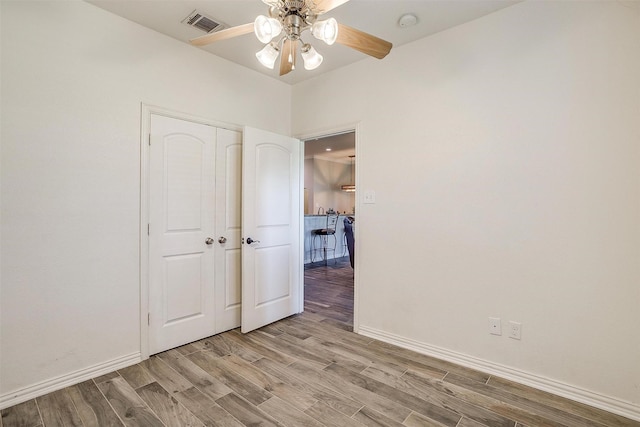 unfurnished bedroom featuring light wood-style floors, a ceiling fan, baseboards, visible vents, and a closet