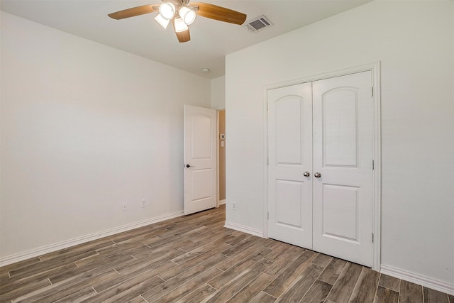 unfurnished bedroom with ceiling fan, visible vents, wood finished floors, baseboards, and a closet