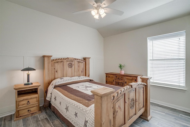 bedroom with baseboards, ceiling fan, vaulted ceiling, and wood finished floors