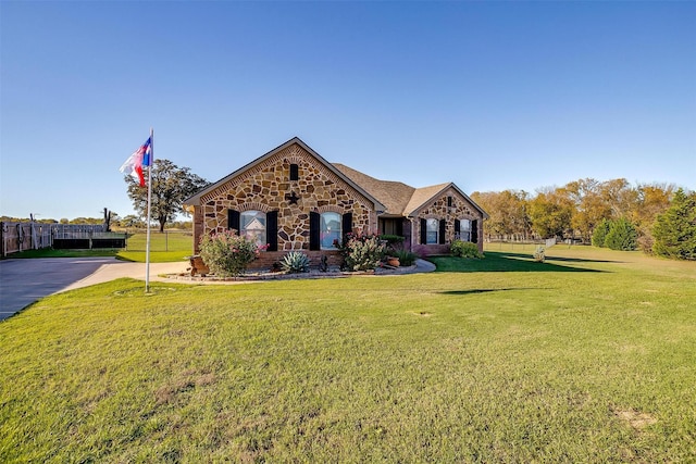 view of front of house featuring a front lawn, fence, and stone siding