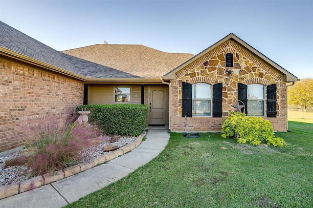 view of front of property with brick siding, a shingled roof, and a front yard