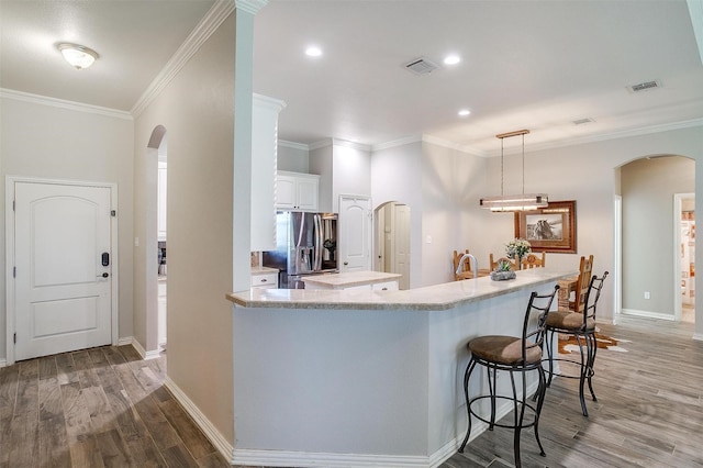 kitchen featuring arched walkways, visible vents, and stainless steel fridge with ice dispenser
