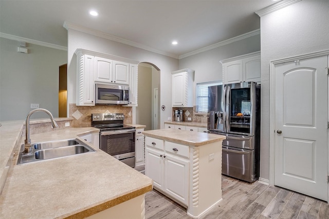 kitchen featuring a sink, arched walkways, stainless steel appliances, and white cabinetry